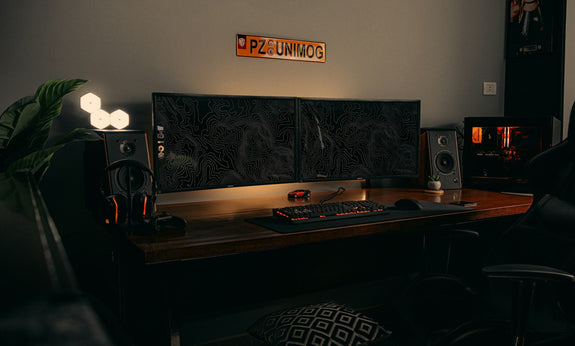 Black flat-screen computer monitor on a brown wooden desk, showcasing an essential element to set up a gaming room with a clean and organized layout.